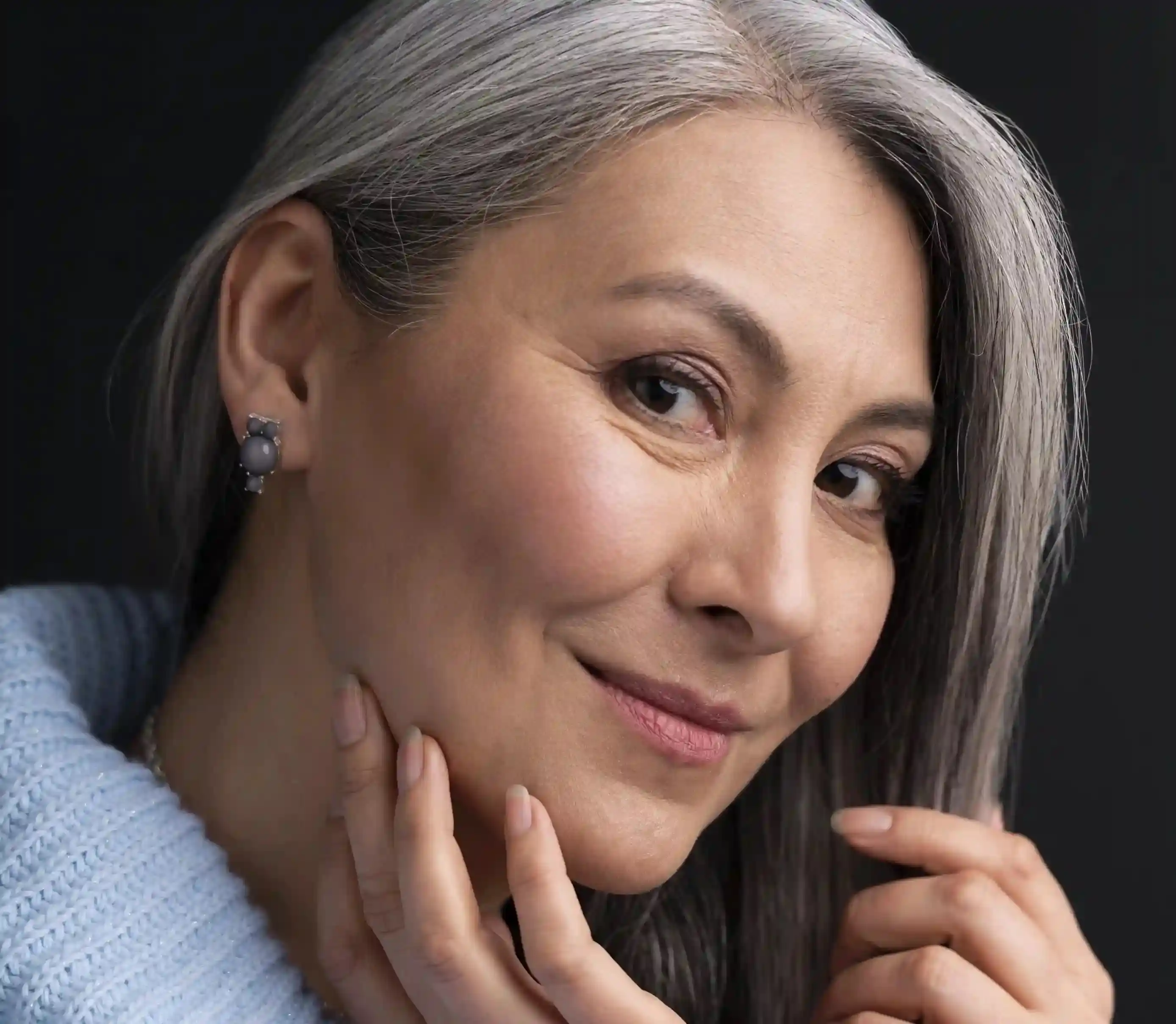 Rosto feminino maduro sorrindo, pele iluminada.